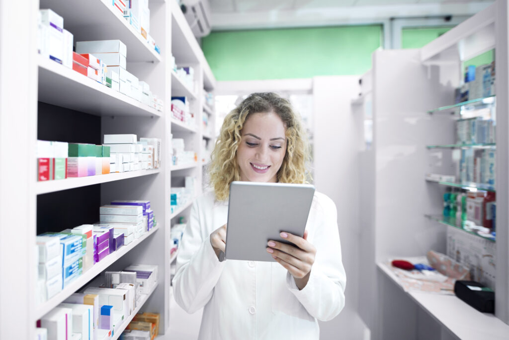 Farmacéutica con una tableta en la farmacia dispensando con receta electrónica